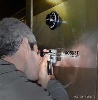 safe technician viewing internal mechanism in safe (safe opening)